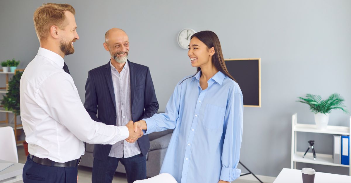 menina vestida de azul menor aprendiz que acabou de ser contratada, apertando a mão de um homem de camisa branca