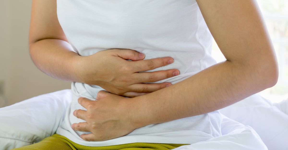 Mulher com a mão na barriga tendo uma constipação