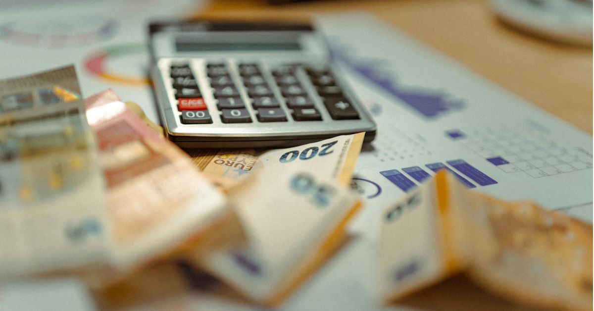 calculadora e notas de dinheiro em cima de uma mesa, referindo-se ao orçamento pessoal